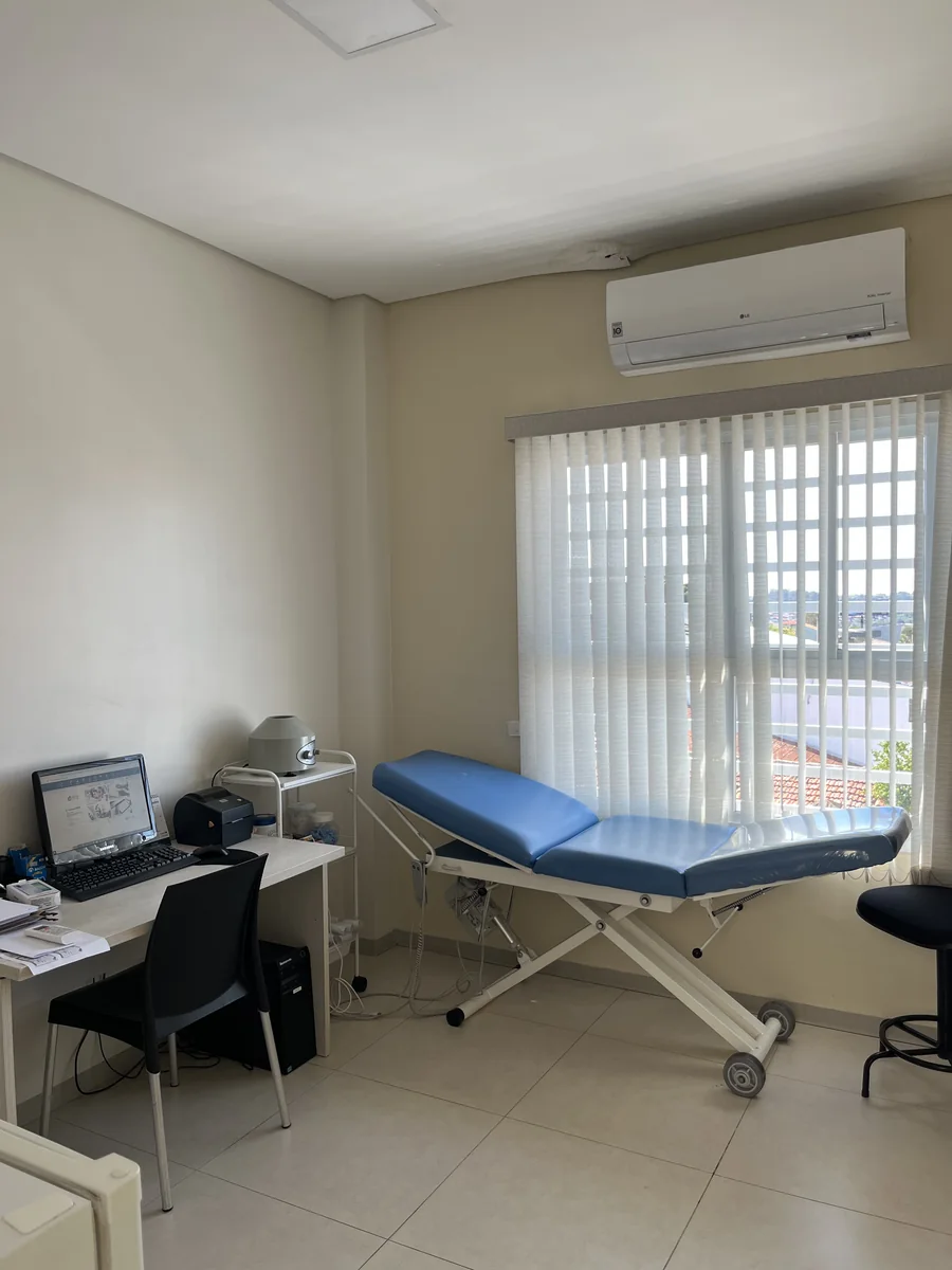 Sala de exames com maca, computador e ar-condicionado