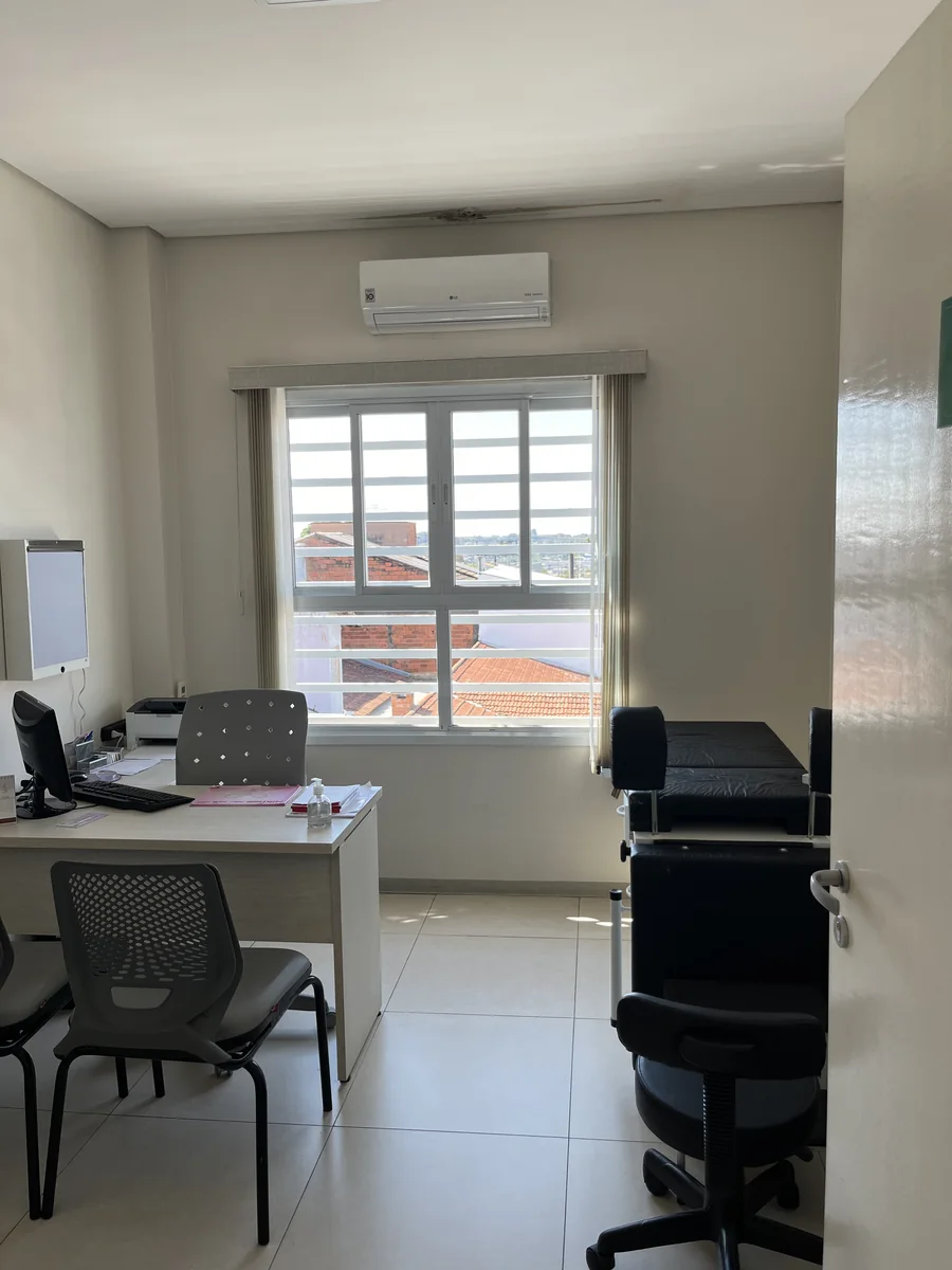 Consultório com mesa, cadeiras e maca