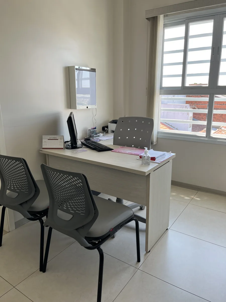 Espaço de atendimento com mesa, cadeiras e janela