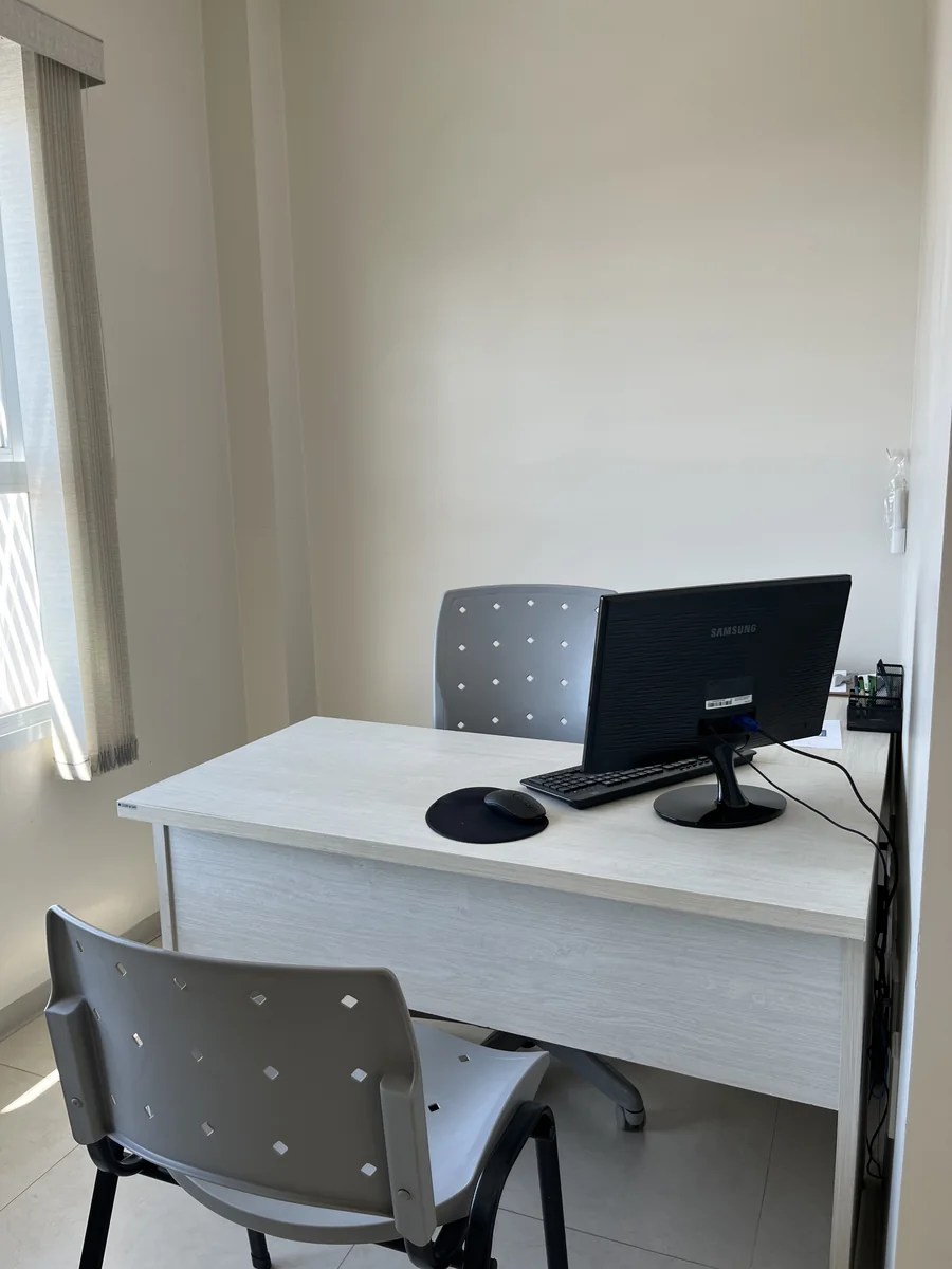 Consultório com mesa, computador e cadeira